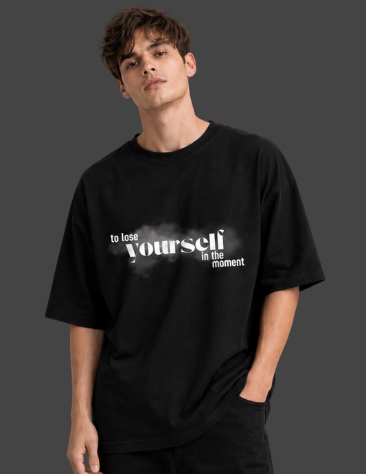 Person wearing a black t-shirt with motivational quote on a dark background
