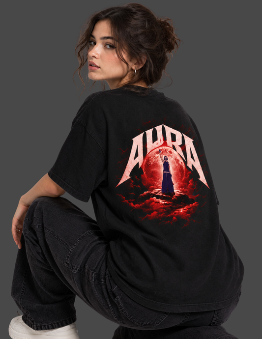 A woman wearing a black oversized T-shirt with a large red and white 'AURA' graphic on the back, posed against a dark gray studio background.