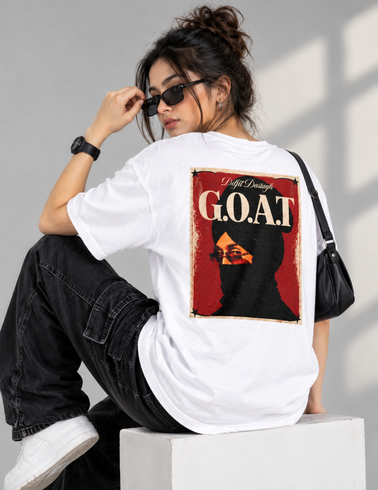 A woman sits on a white block wearing a white t-shirt with a large back graphic that reads 'G.O.