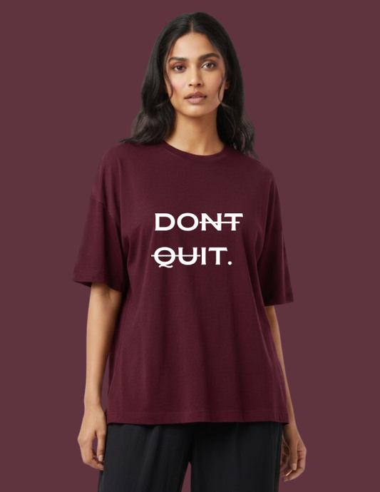 Woman wearing a maroon t-shirt with 'DON'T QUIT.' text on a dark red background