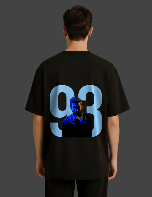 Person wearing a black t-shirt with a graphic of a man and the number 93 on the back against a dark background