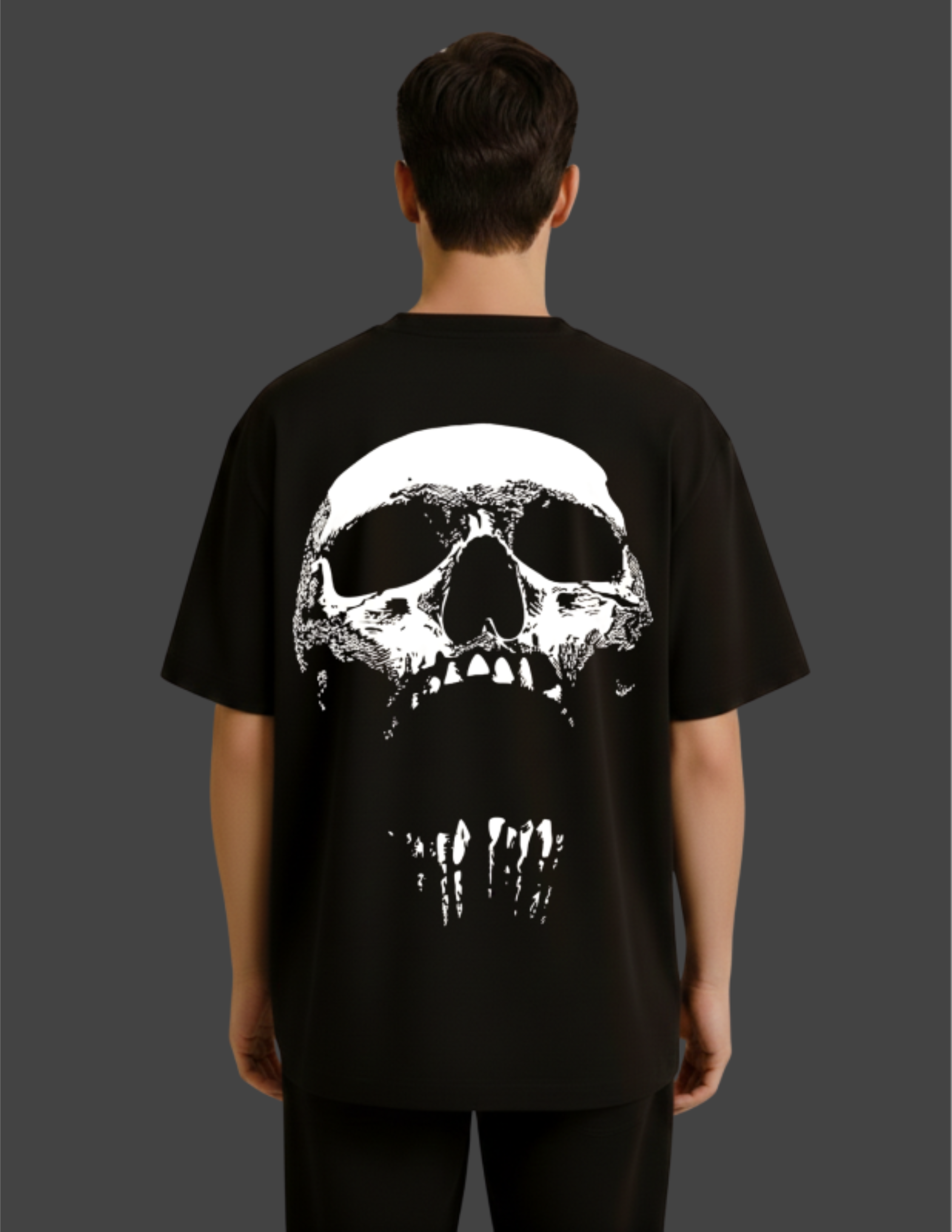 Person wearing a black t-shirt with a white skull design on the back against a dark background