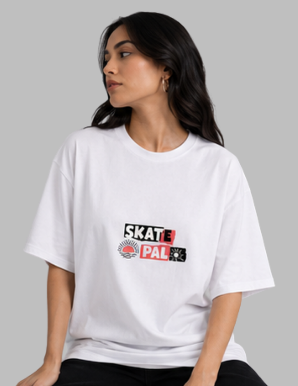 A woman wearing a white short-sleeve t-shirt with a 'Skate Pal' graphic on the chest, posed against a solid gray background.