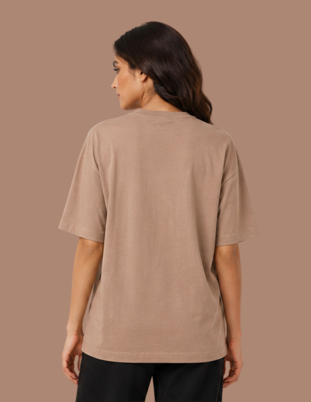 A woman shown from the back wearing a plain taupe short-sleeve t-shirt and black pants, set against a solid taupe background.