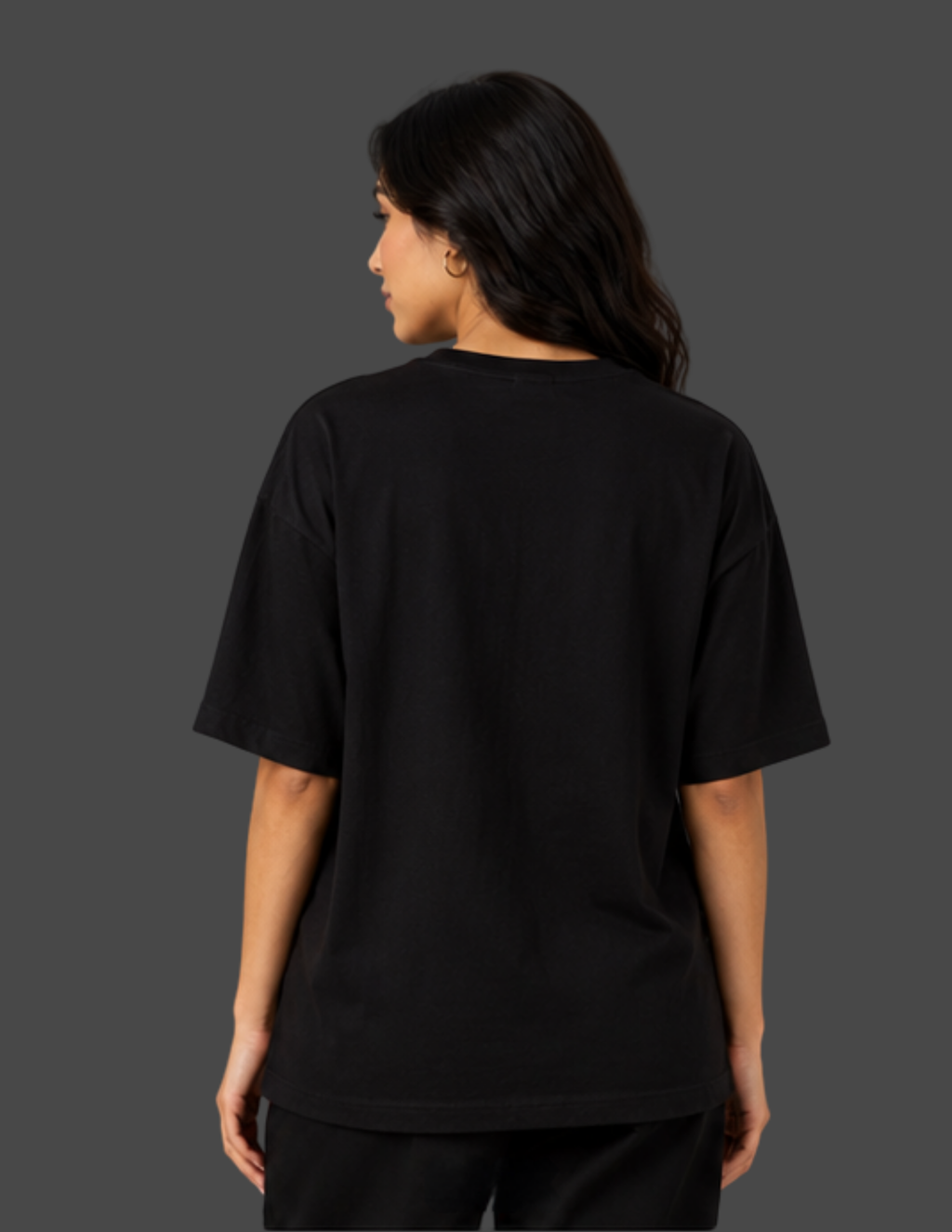 A woman shown from the back wearing an oversized black short-sleeve t-shirt against a dark gray studio background.