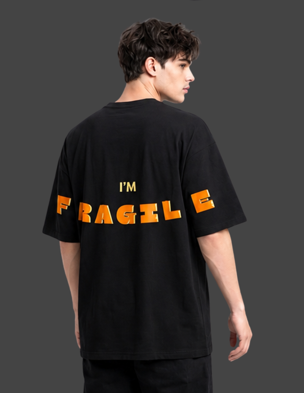Person wearing a black t-shirt with 'I'm Fragile' text on the back against a dark background
