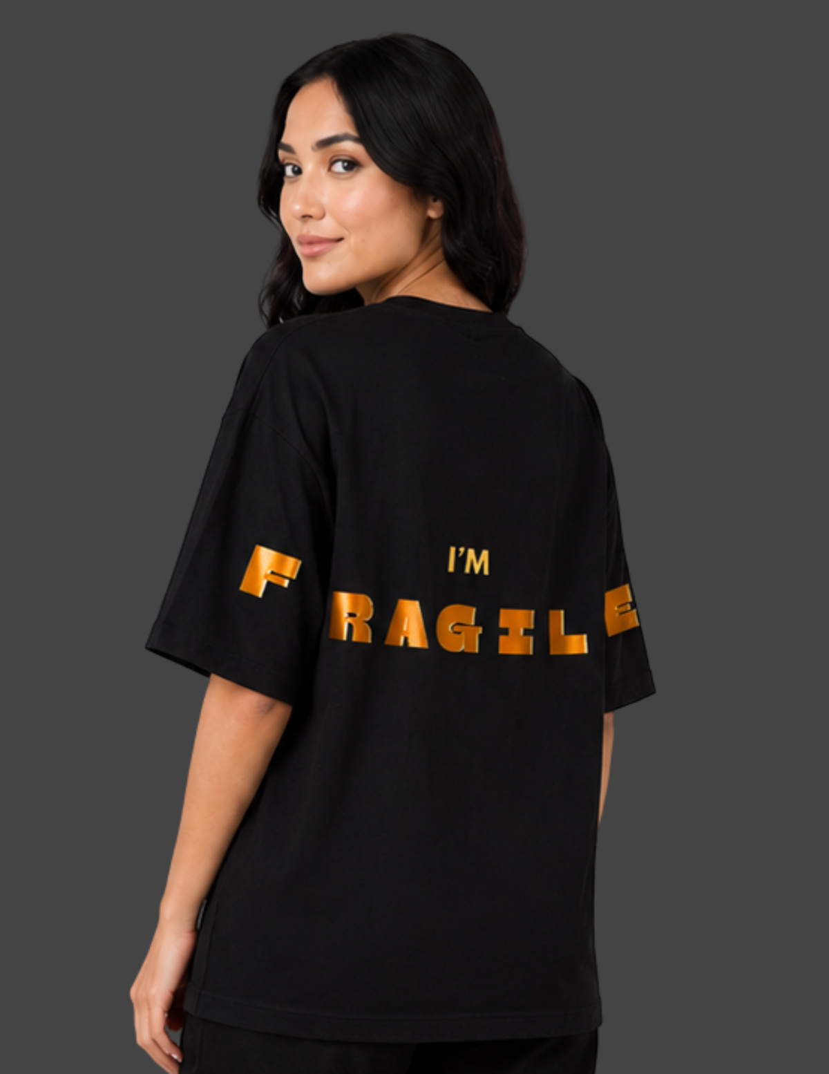 Person wearing a black t-shirt with 'I'm Fragile' text on the back against a dark background