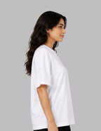 A woman with long, wavy dark hair is shown in profile wearing a plain white short-sleeve crewneck t-shirt against a solid gray studio background.