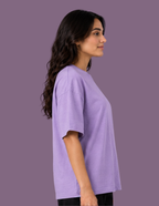 A woman shown in side profile wearing an oversized short-sleeve crewneck t-shirt in light purple, set against a solid purple studio background.