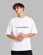 Person wearing a white t-shirt with 'TRANQUIL' text on a gray background