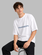 Person wearing a white t-shirt with 'TRANQUIL' text on a gray background