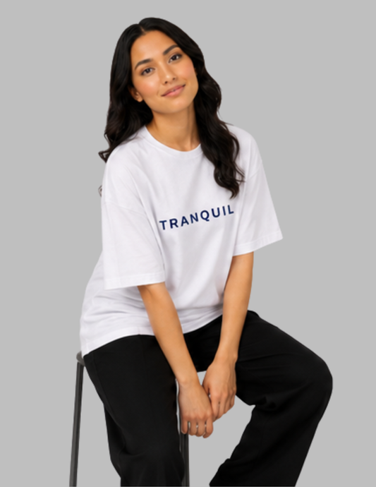 Woman wearing a white 'TRANQUIL' t-shirt on a gray background