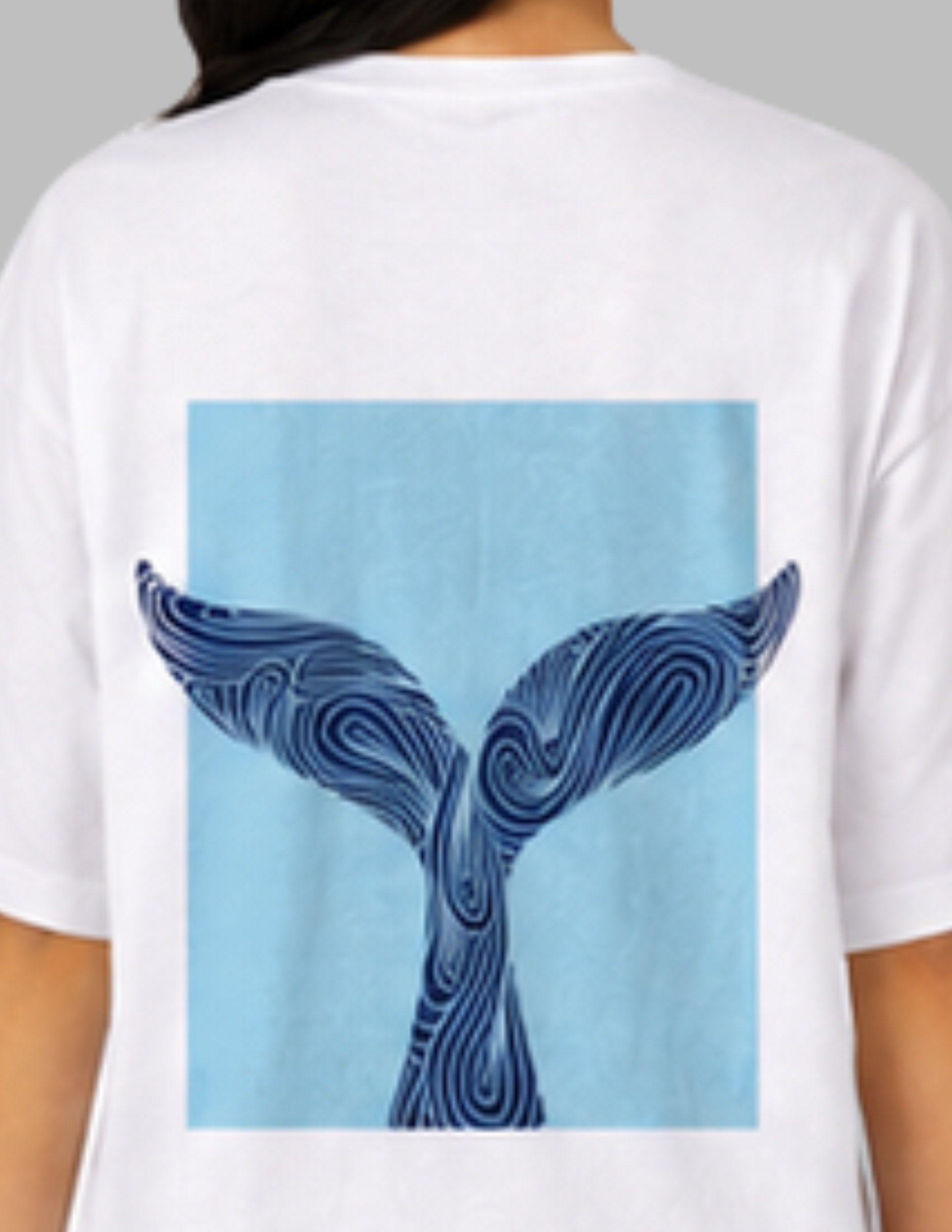 White t-shirt with a blue whale tail design on the back, worn by a person.