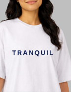 Person wearing a white t-shirt with 'TRANQUIL' text on a gray background