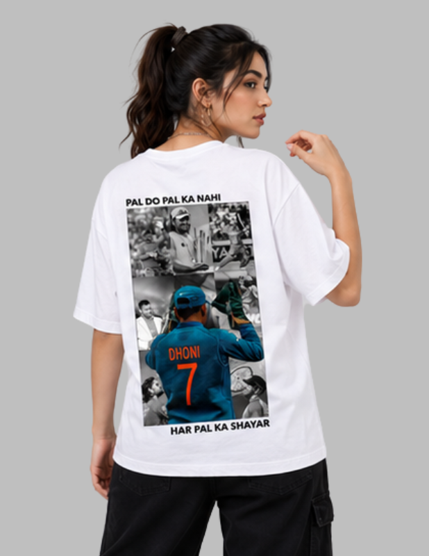 A woman modeling a white oversized T-shirt from the back, featuring a large graphic print of Indian cricketer Dhoni in a blue jersey with the number 7, surrounded by black-and-white photos and the text 'PAL DO PAL KA NAMI' and 'HAR PAL KA SHAYAR'.
