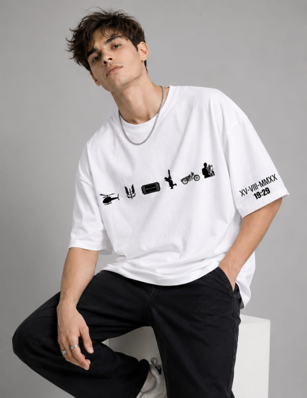 A man wearing a white oversized t-shirt with black graphic prints on the chest and sleeve, paired with black pants, posing against a neutral gray background.