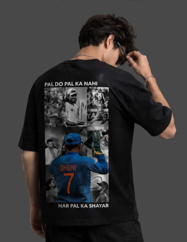 A man shown from behind wearing a black t-shirt with a large graphic print on the back. The print features a collage of images, including a blue jersey with the name 'DHONI' and number '7', along with white text reading 'PAL DO PAL KA NAHI' at the top and 'HAR PAL KA SHAYAR' at the bottom.