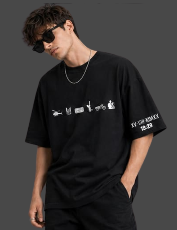 A man wearing a black oversized graphic t-shirt with white printed designs on the front and sleeve, styled with black pants, sunglasses, and a silver chain necklace against a dark gray background.
