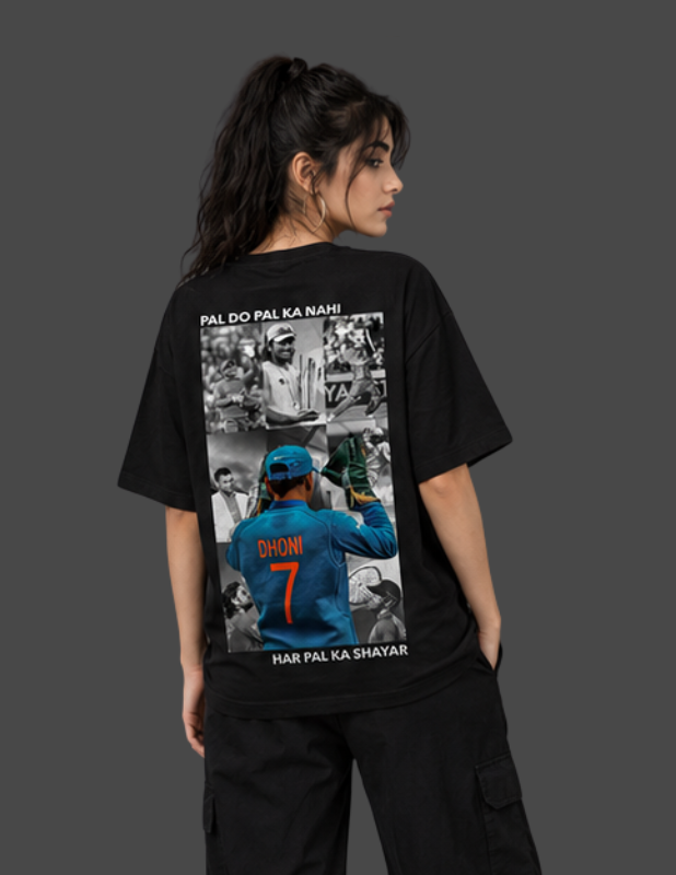 A woman shown from the back wearing a black graphic T-shirt with a large printed collage on the back featuring cricket imagery and text, paired with black cargo pants against a dark gray studio background.