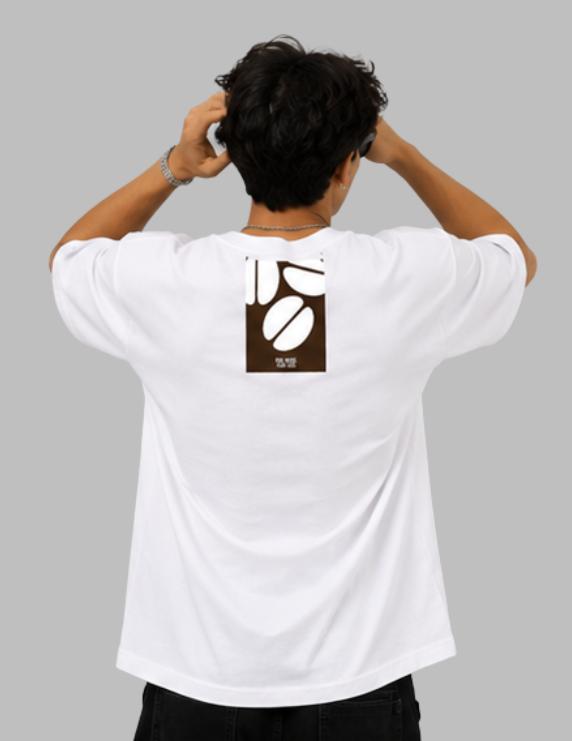 A man viewed from behind wearing a white t-shirt with a brown coffee bean graphic on the back, set against a solid gray background.