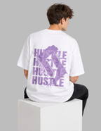 Person wearing a white t-shirt with purple text on the back, sitting on a white cube against a gray background.