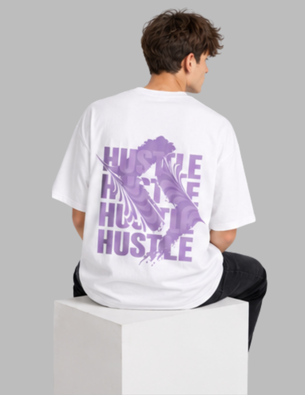 Person wearing a white t-shirt with purple text on the back, sitting on a white cube against a gray background.