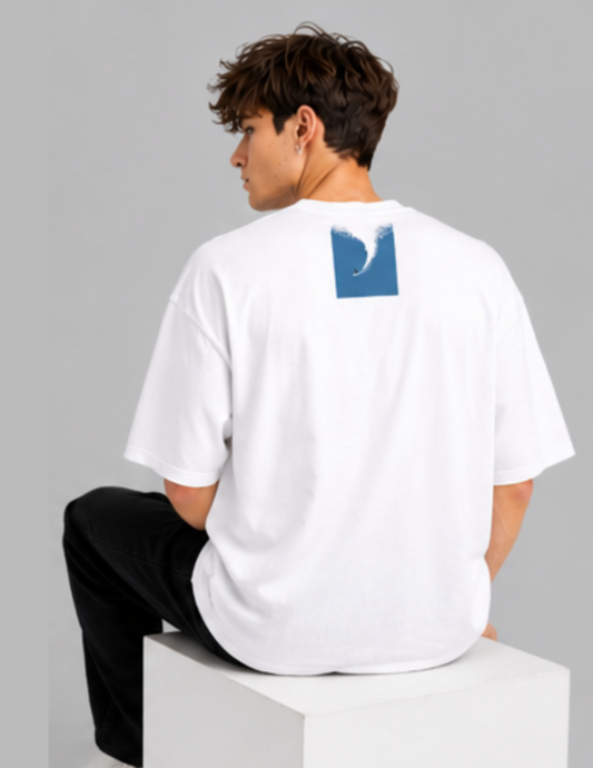 Person wearing a white t-shirt with a blue graphic on the back, sitting on a gray background