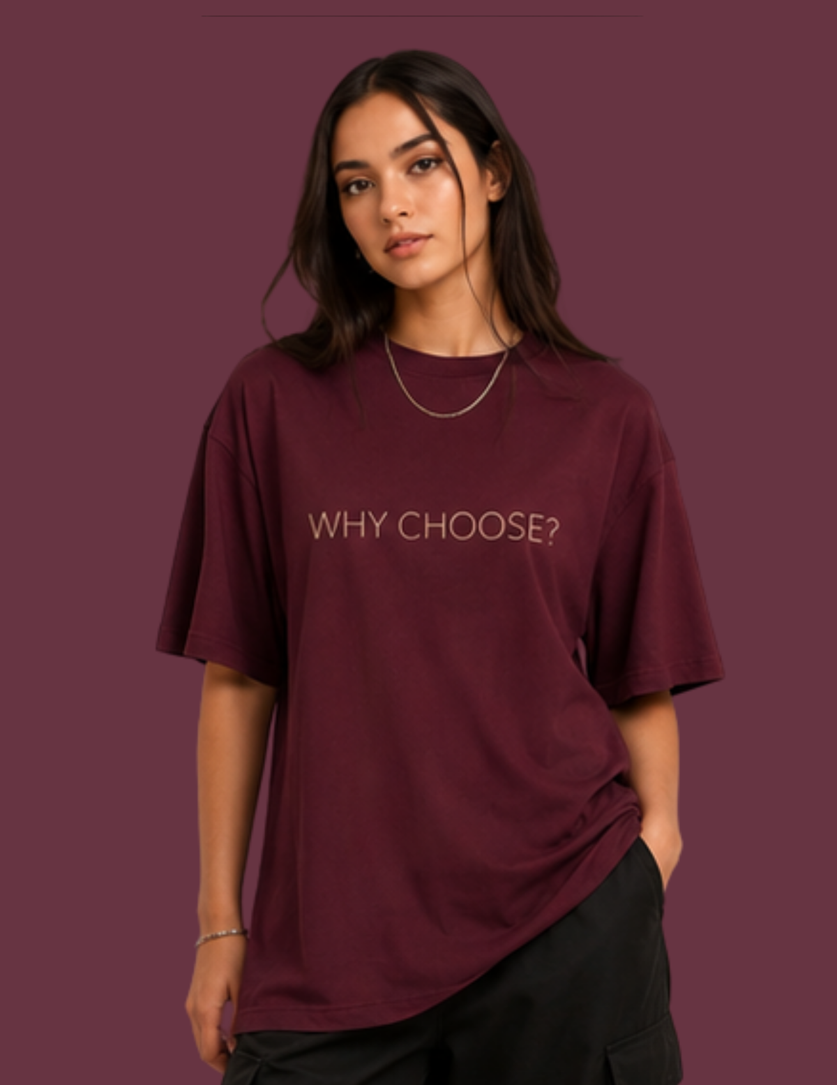 A woman wearing an oversized maroon t-shirt with the words 'WHY CHOOSE?' printed in gold across the chest, posed against a solid maroon background.