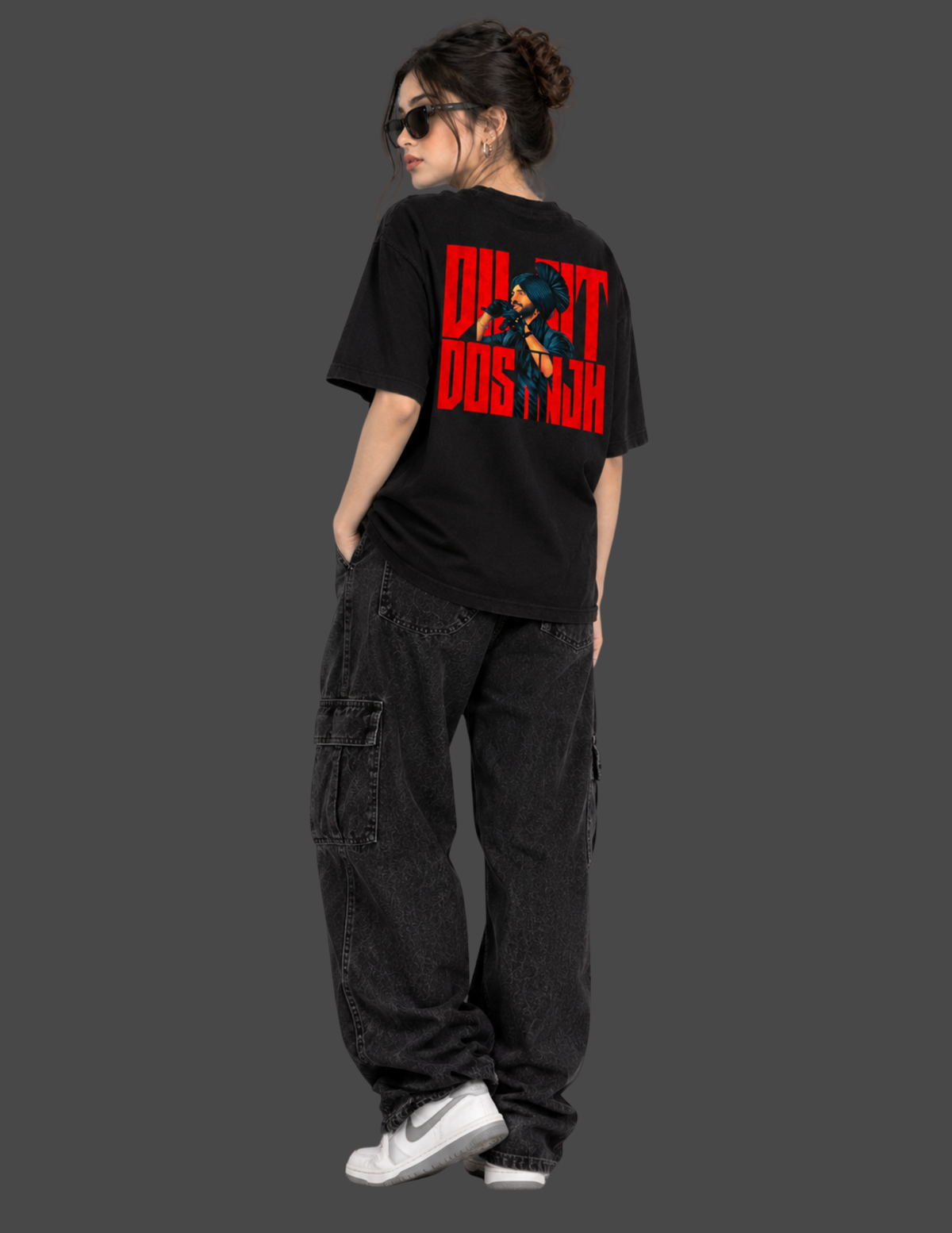 A model from the back wearing a black t-shirt with a bold red graphic print that reads 'DON'T TREAD ON FEAR' and dark cargo pants, set against a solid dark gray background.