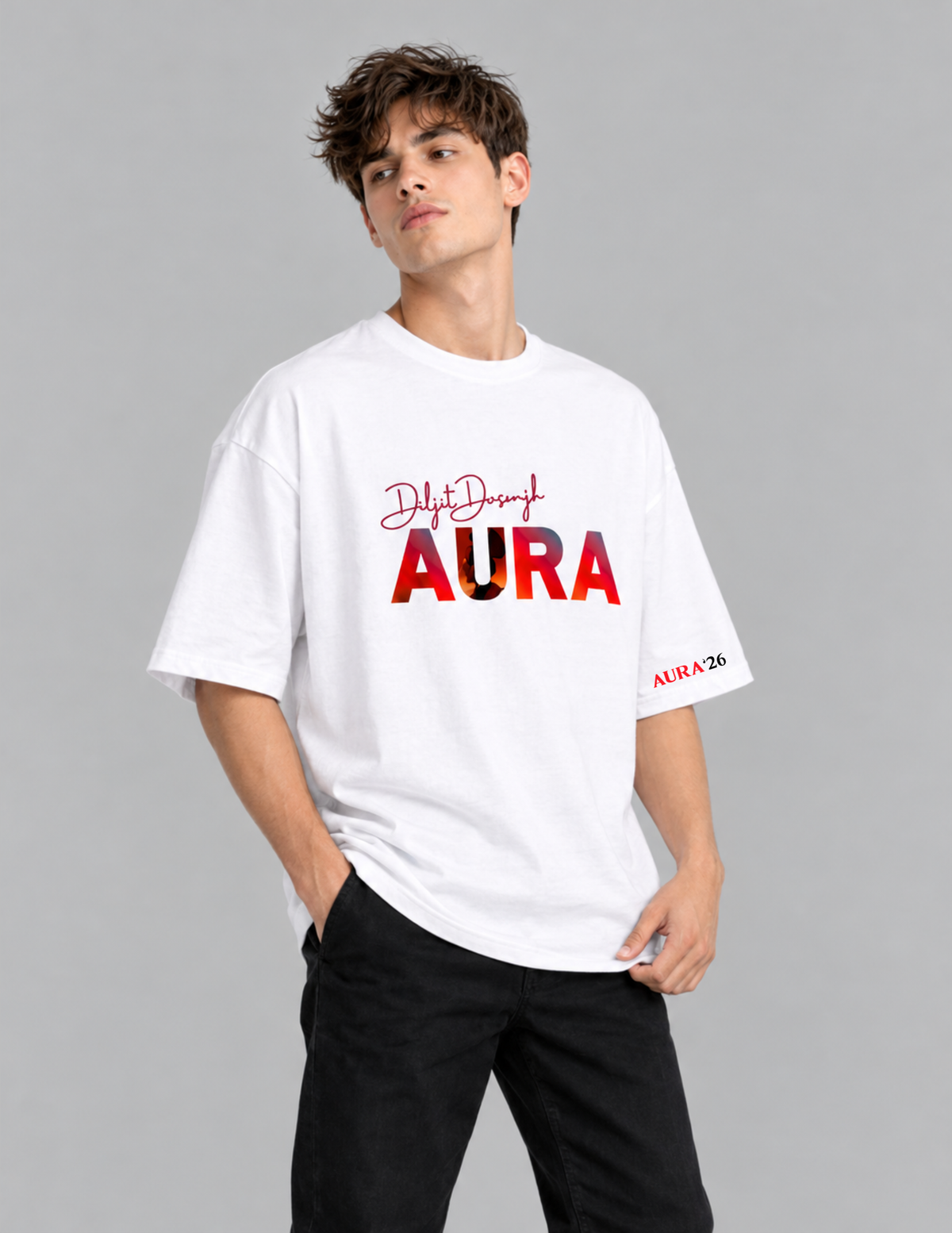 A man wearing a white oversized t-shirt with 'Dylan Design AURA' printed on the front, paired with black pants, against a solid gray studio background.