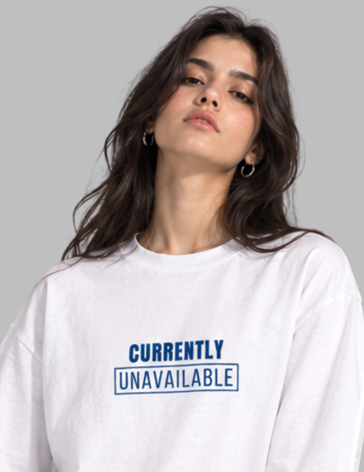 A woman wearing a white crewneck sweatshirt with the text 'CURRENTLY UNAVAILABLE' printed in blue on the chest, set against a solid gray background.
