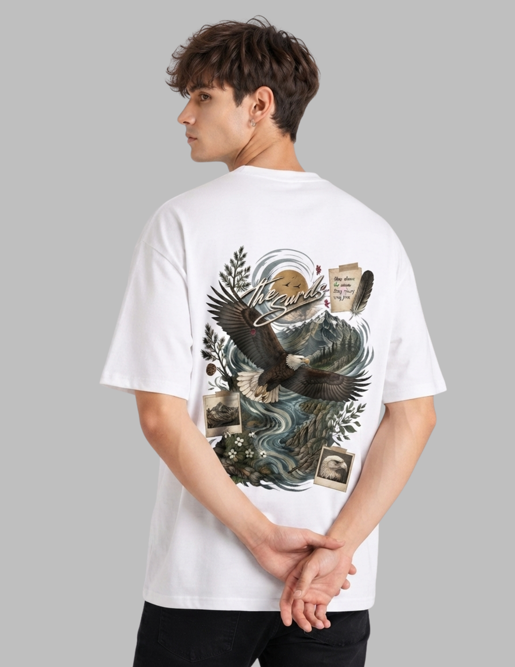A man wearing a white short-sleeve t-shirt, viewed from the back. The shirt features a large graphic print on the back with an eagle, waves, foliage, and collage-style elements.