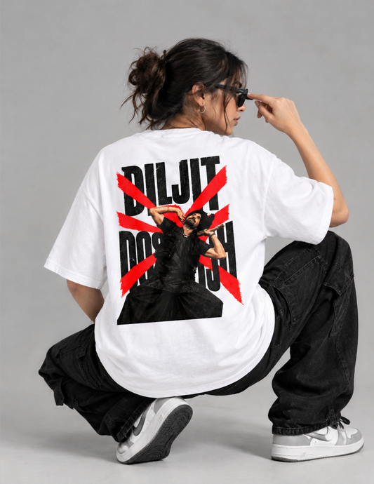 A model wearing a white oversized t-shirt with a graphic print of the band Diljit Dosanjh, shown from the back while crouching. The shirt features a black graphic of the artist and a bold red diagonal X over the text 'DILJIT DOSANJH'.