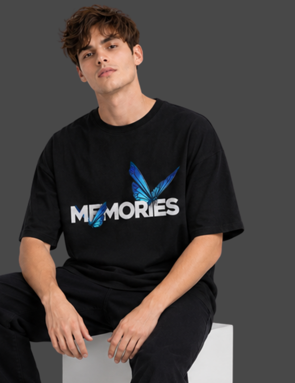 Person wearing a black t-shirt with 'MEMORIES' and butterfly design on a gray background