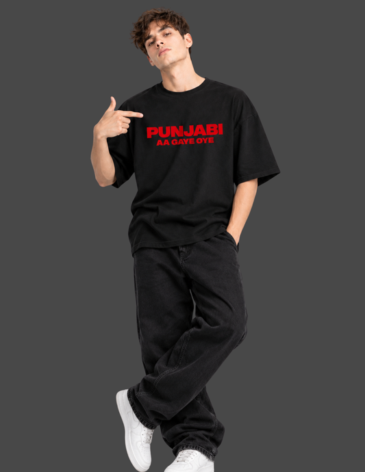 A man modeling a black t-shirt with red text that reads 'PUNJABI AA GAVE OYE' against a solid dark gray background.