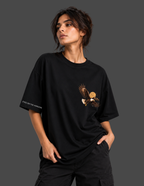 A woman modeling a black oversized t-shirt with a graphic of a flying eagle carrying a sun on the left chest, and white text on the right sleeve reading 'EYES ON THE ENTHUSIASM'.