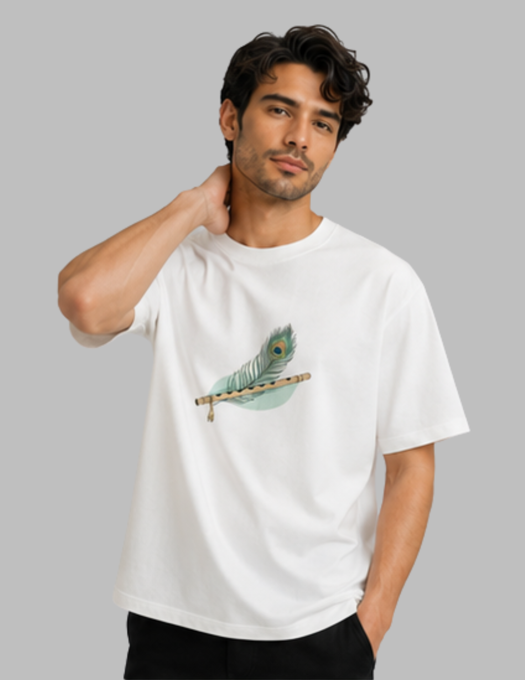 A man wearing a white short-sleeve crewneck t-shirt with a graphic of a teal peacock feather resting on a wooden flute, set against a solid gray background.
