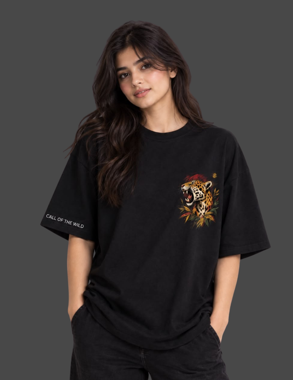 A woman modeling a black oversized t-shirt with a colorful leopard graphic on the left chest and 'CALL OF THE WILD' text on the right sleeve, set against a dark gray background.