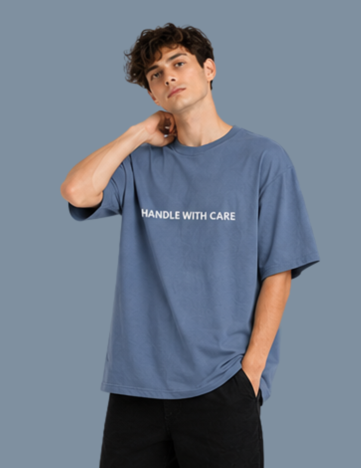 Man wearing a blue t-shirt with 'HANDLE WITH CARE' text on a gray background
