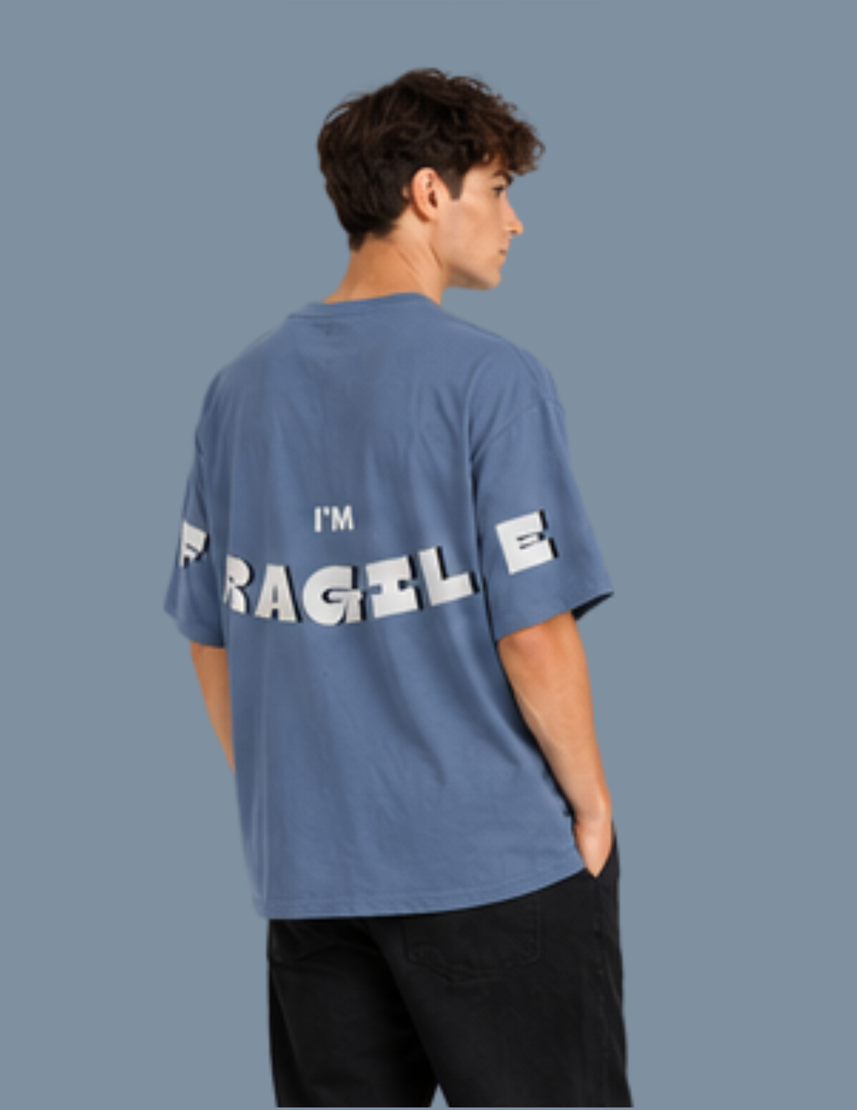 Person wearing a blue t-shirt with text on the back against a gray background