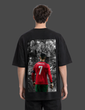 Person wearing a black t-shirt with a graphic of a soccer player in a red jersey on the back.