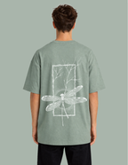 Person wearing a green t-shirt with a white dragonfly design on the back against a gray background