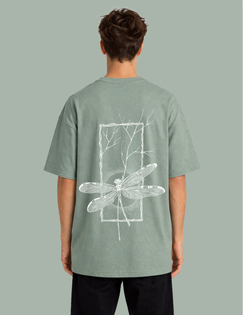 Person wearing a green t-shirt with a white dragonfly design on the back against a gray background