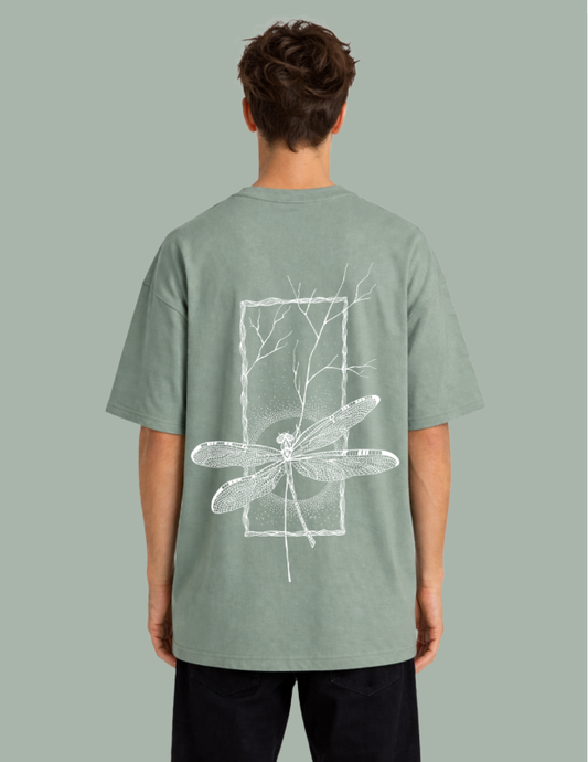 Person wearing a green t-shirt with a white dragonfly design on the back against a gray background