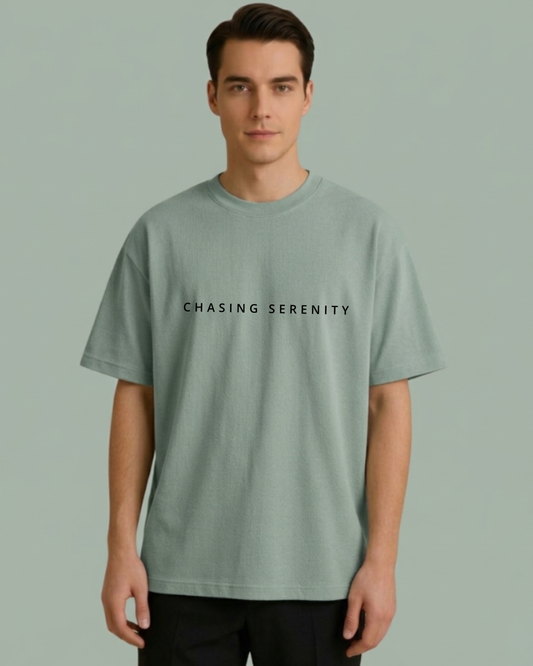 Person wearing a light green t-shirt with 'CHASING SERENITY' text on a plain background