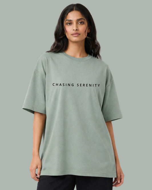 Woman wearing a light green t-shirt with 'CHASING SERENITY' text on a gray background