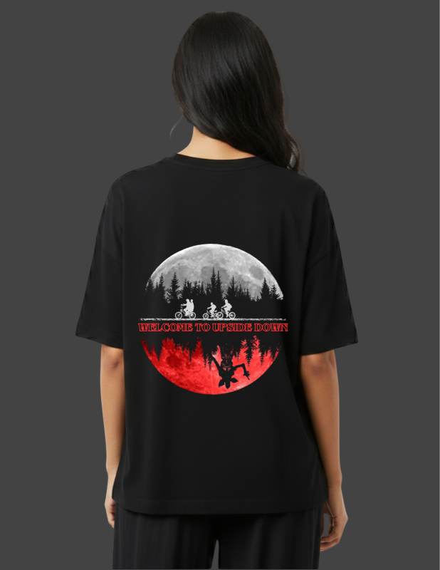 Person wearing a black t-shirt with a graphic design on the back, featuring a moon and silhouette of a forest.