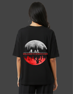 Person wearing a black t-shirt with a graphic design on the back, featuring a moon and silhouette of a forest.
