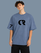 Person wearing a blue t-shirt with a black logo on a gray background