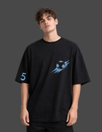 Person wearing a black t-shirt with a blue graphic design on a dark background